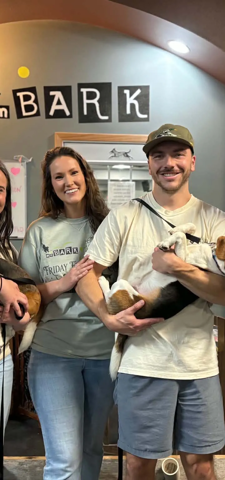 Four Finding Eden Rescue volunteers holding two beagles under an emBARK sign