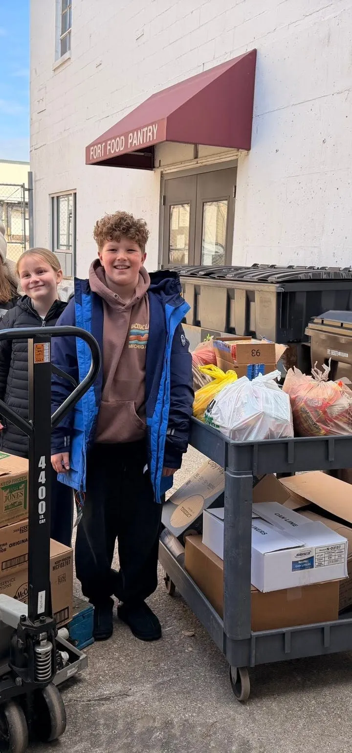 Three young volunteers with a loaded cart outside the Fort Atkinson Food Pantry door