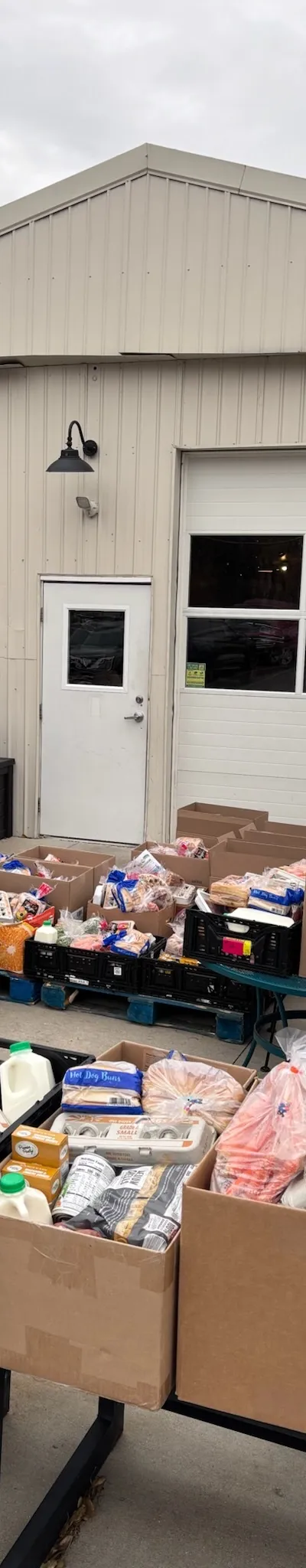 Crates and boxes of bread, milk, and produce set out for the monthly food pantry