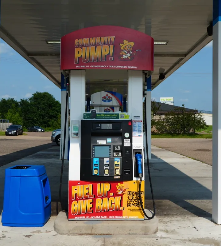 A fuel pump under the canopy with a Community Pump sign above it reading you fuel up, we give back, our community benefits