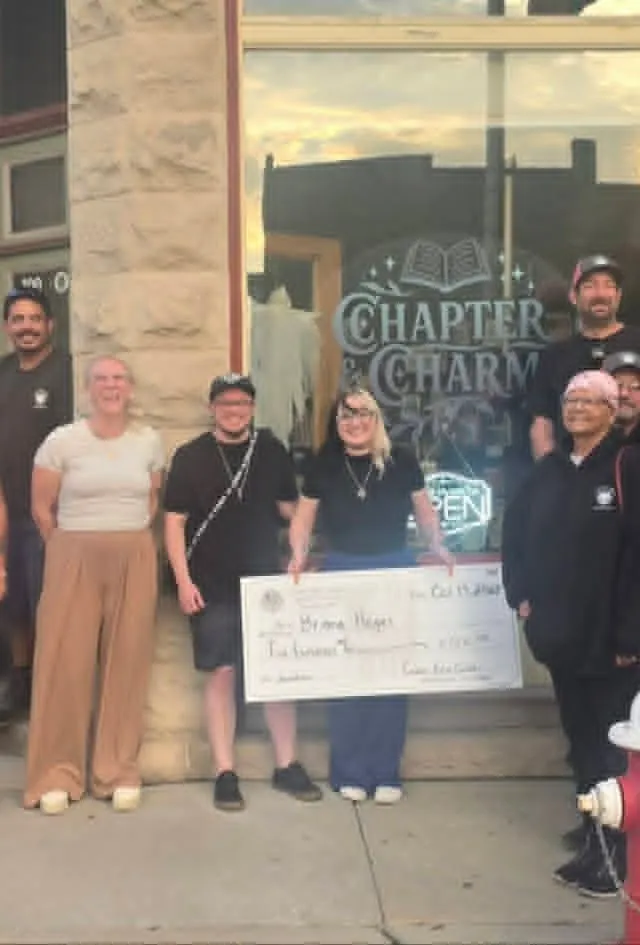 Club members presenting a cheque outside a Main Street shopfront