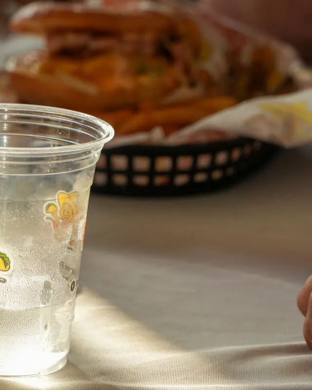 A cup printed with the Speedy Tacos character, a basket of food behind it