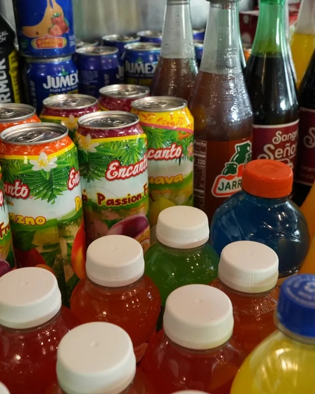 Bottles and cans of Mexican sodas and fruit juices packed onto a shelf